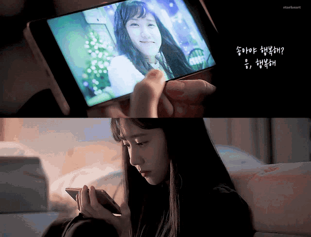 a woman sitting on a couch looking at a cell phone with korean writing on the bottom