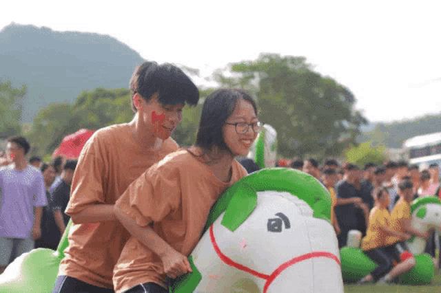 a man and a woman are riding a green and white inflatable horse