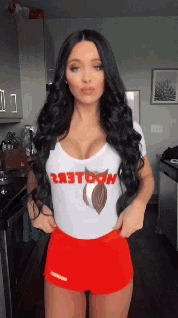 a woman wearing hooters shorts and a shirt with an owl on it