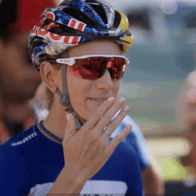 a woman wearing a helmet and sunglasses has a ring in her finger