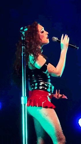 a woman in a red skirt is dancing in front of a blue background