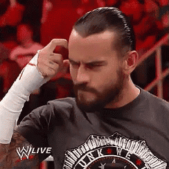 a man with a beard is scratching his head while wearing a wwe shirt .