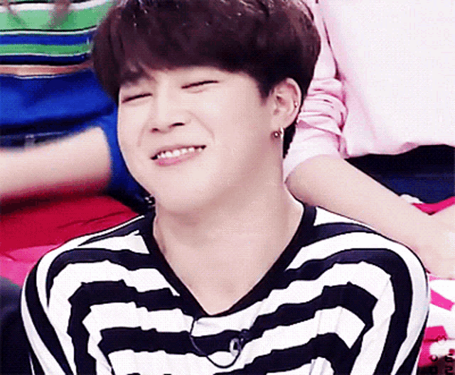 a man wearing a black and white striped shirt is smiling with his eyes closed