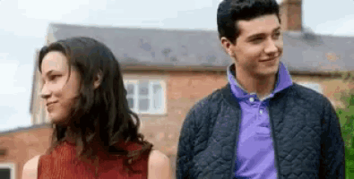 a man and a woman are standing next to each other in front of a brick house .