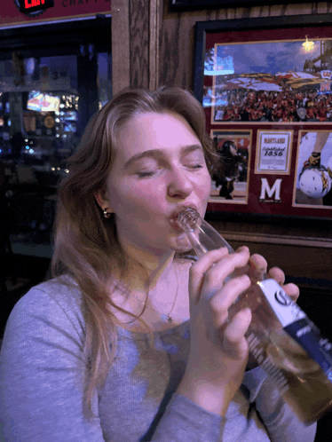 a woman is drinking from a bottle of corona
