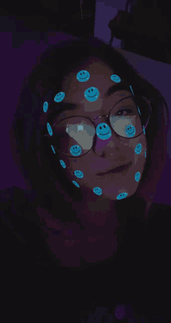 a girl wearing glasses has smiley faces painted on her face