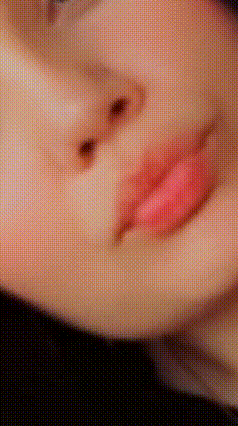 a close up of a woman 's face with pink lips and a blurry background .
