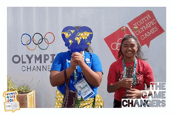 two girls are posing for a photo in front of a sign that says youth olympic games
