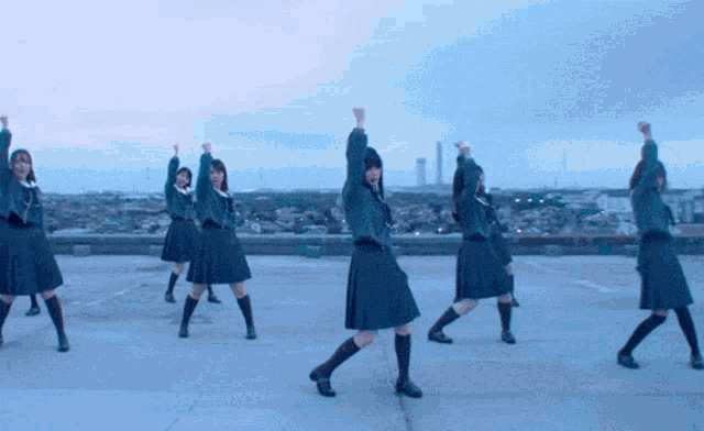a group of girls are dancing on a rooftop with their arms in the air