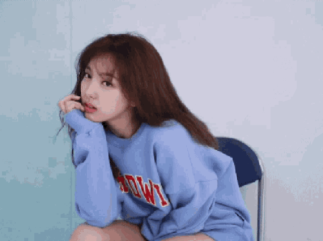 a woman wearing a blue sweatshirt with the word bowl on it sits in a chair