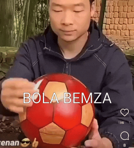 a man is holding a red soccer ball with the words bola bemza written on it