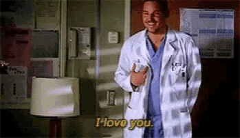 a man in a lab coat is standing in a room and saying i love you .