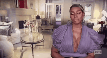 a woman in a purple dress is sitting in a living room with a table .