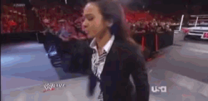 a woman in a black suit is standing in front of a crowd on a tv screen that says wwe live