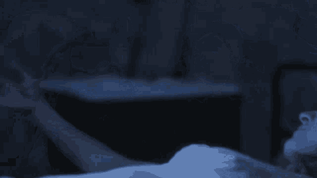 a woman in a white tank top is laying in bed