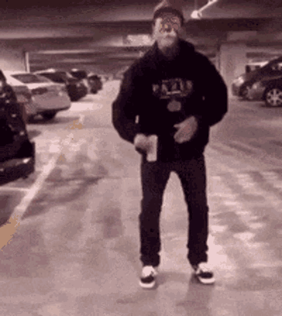 a man is standing in a parking garage holding a piece of paper in his hand