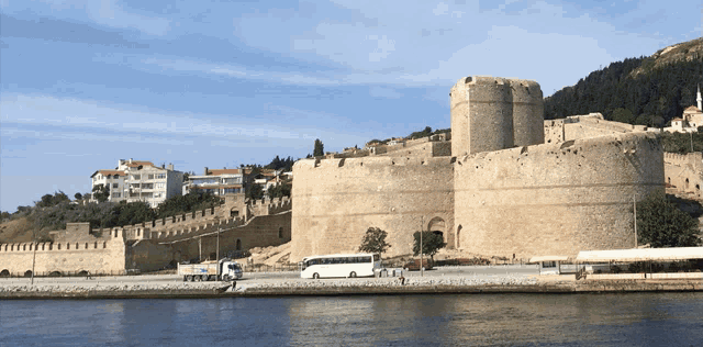 a white bus is parked in front of a large stone castle