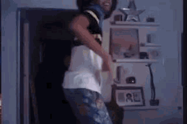 a man is dancing in front of a shelf in a room .