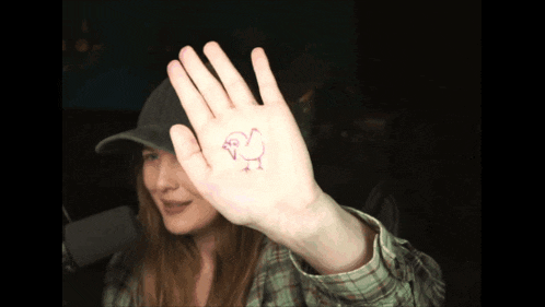 a woman shows a drawing of a chicken on her hand