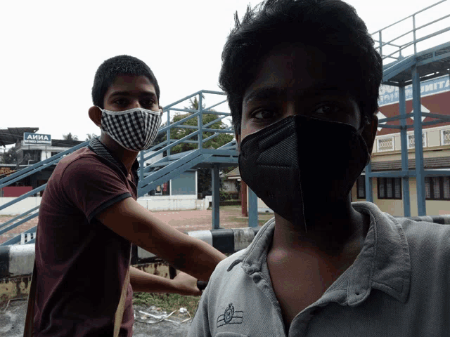 a man wearing a mask stands next to another man wearing a mask in front of a sign that says aisha