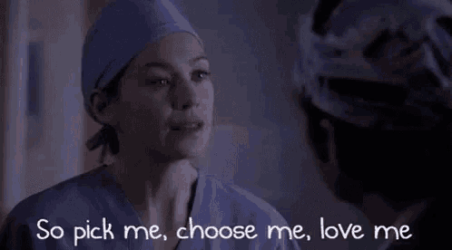 a woman in scrubs is talking to a man in a surgical cap in a hospital room .