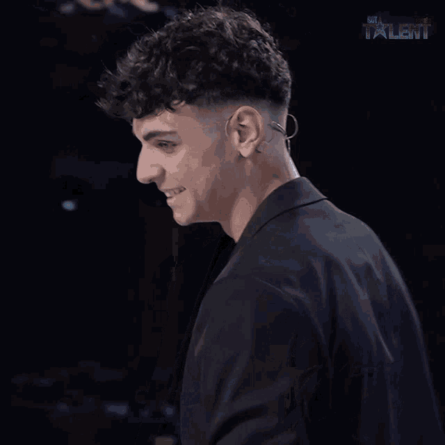 a man wearing a black jacket and a black t-shirt with the word talent on the bottom left