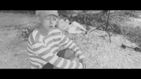 a black and white photo of a young boy sitting on the ground .