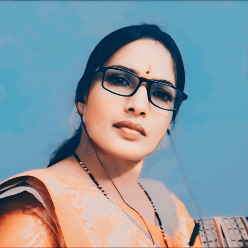 a woman wearing glasses has a red dot on her nose