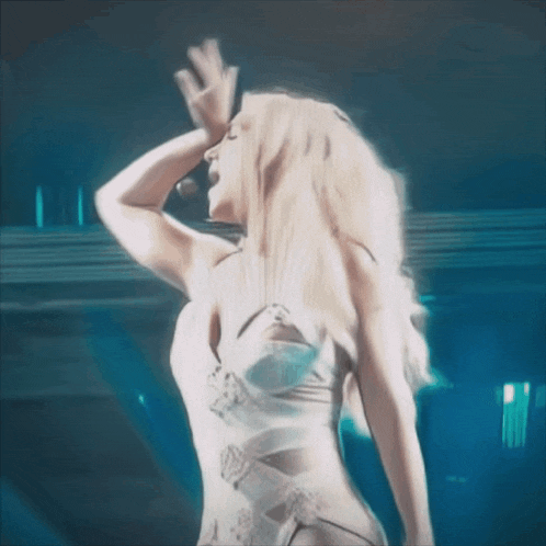 a woman in a white bodysuit is dancing in front of a microphone