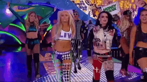 a group of women are dancing on a stage in front of a sign that says money bank .