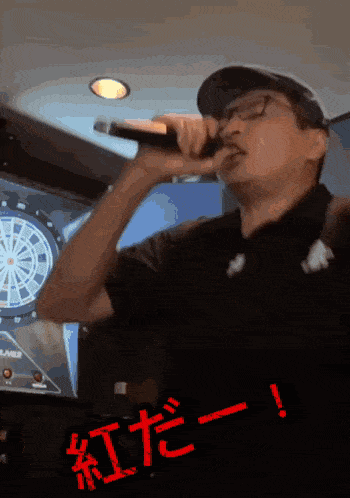 a man singing into a microphone in front of a dart board with chinese writing