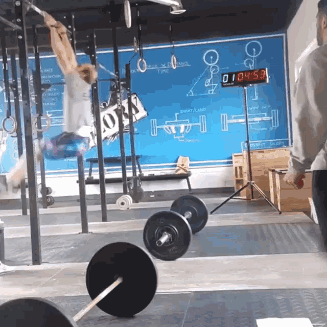 a man is doing a pull up in front of a blue board that says ' workout ' on it