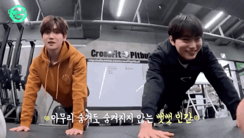 two men do push ups in front of a sign that says crossfit pitbul