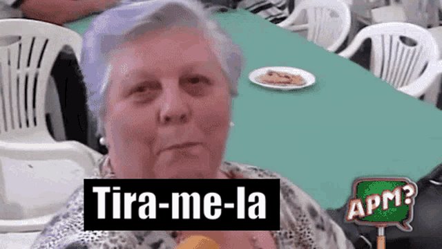 an older woman is sitting at a table with a plate of food and a sign that says apm