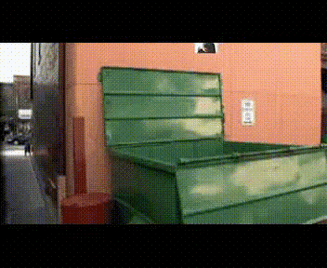 a green dumpster sits in front of a building with a sign on it that says ' a '
