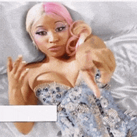 a woman with pink hair is laying in bed holding a stuffed animal