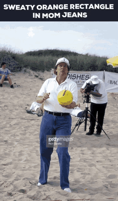 a man wearing sweaty orange rectangle in mom jeans is holding a ball