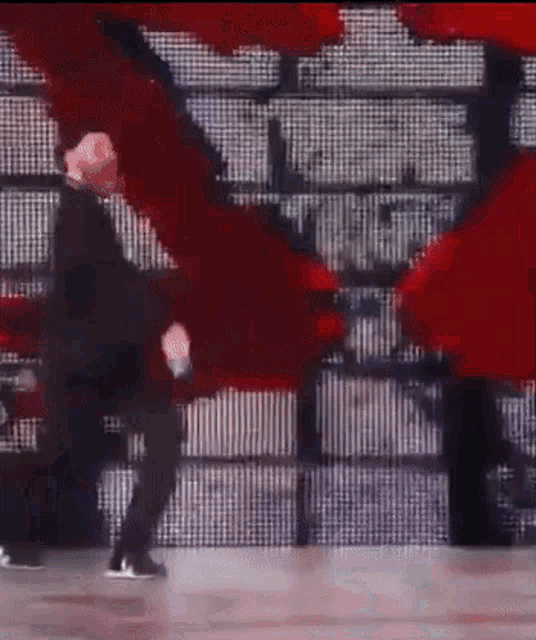 a man is dancing on a stage in front of a wall with red lights .