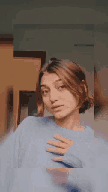 a woman is wearing a blue sweater and taking a selfie .