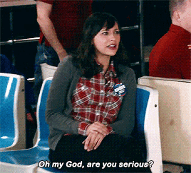 a woman in a plaid shirt is sitting in a chair and says oh my god are you serious ..
