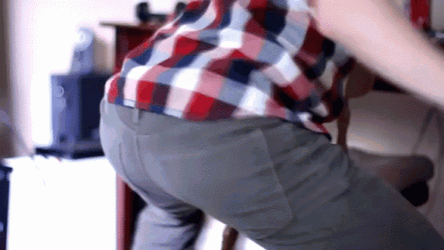 a man in a plaid shirt and gray pants is dancing in a room