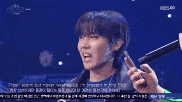 a man singing into a microphone with the words fresh scent but never washed up behind him