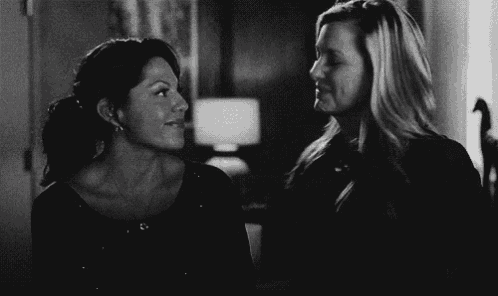 a black and white photo of two women standing next to each other and smiling .