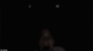 a blurred image of a person 's face in the dark with a few lights behind them