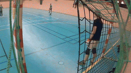 a man in a black shirt is standing in front of a net in a gym