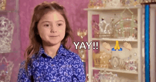 a little girl in a blue shirt is standing in front of a shelf with a shelf full of jewelry .
