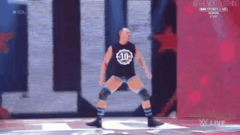a wrestler with the number 10 on his shirt is dancing on a stage