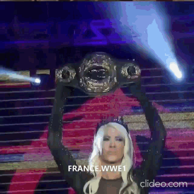 a woman is holding a wrestling championship belt in her hands ..