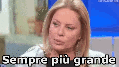 a woman is sitting in front of a blue screen with the words sempre più grande on it