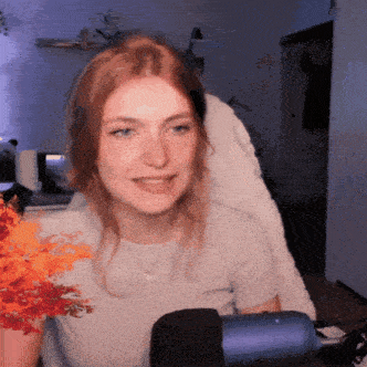 a woman with red hair is sitting in front of a microphone with flowers in her hand .